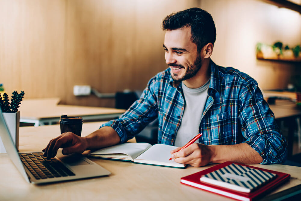 Man sitting at a desk with a notepad and laptop