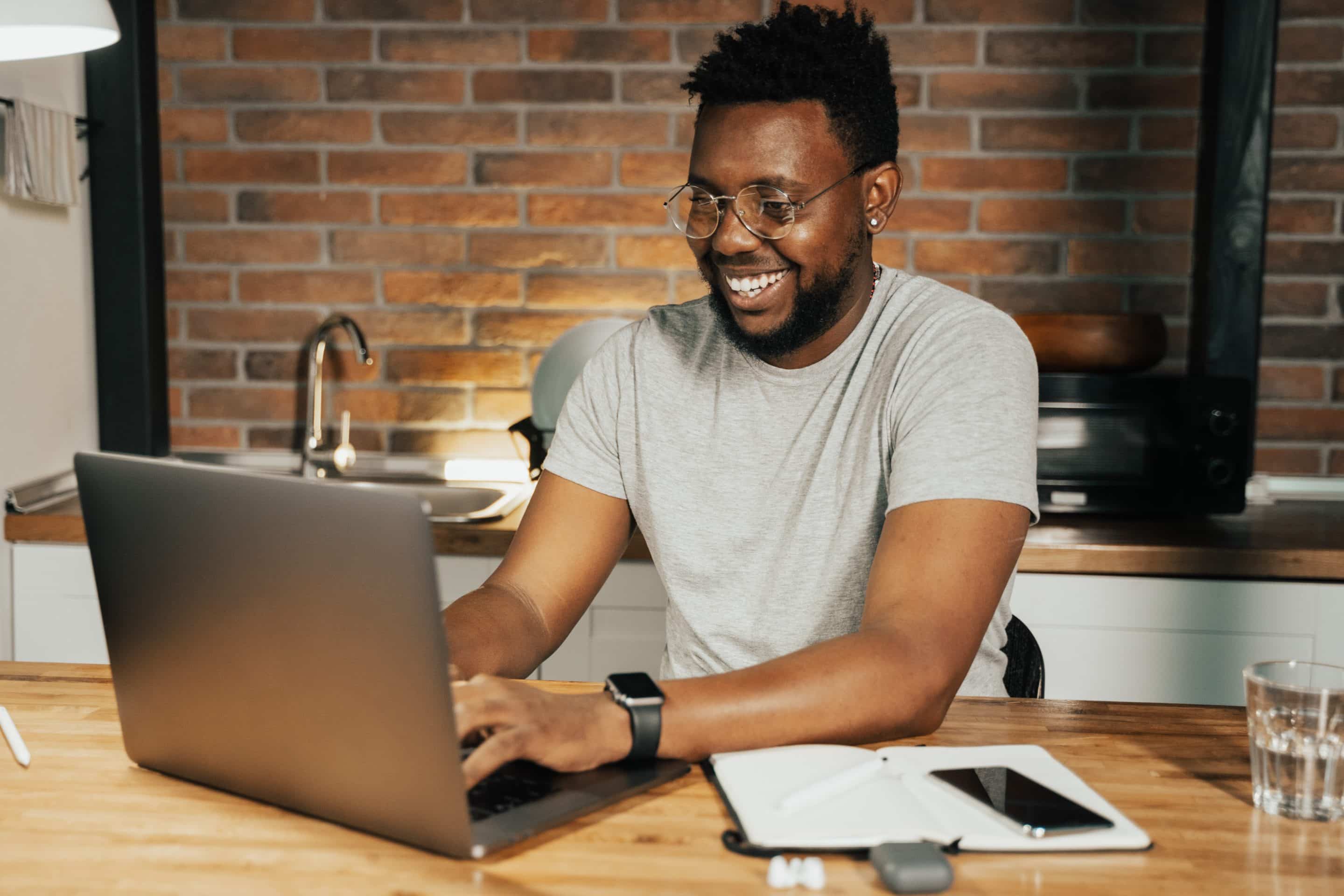 Man sitting at a table with his laptop and a notebook