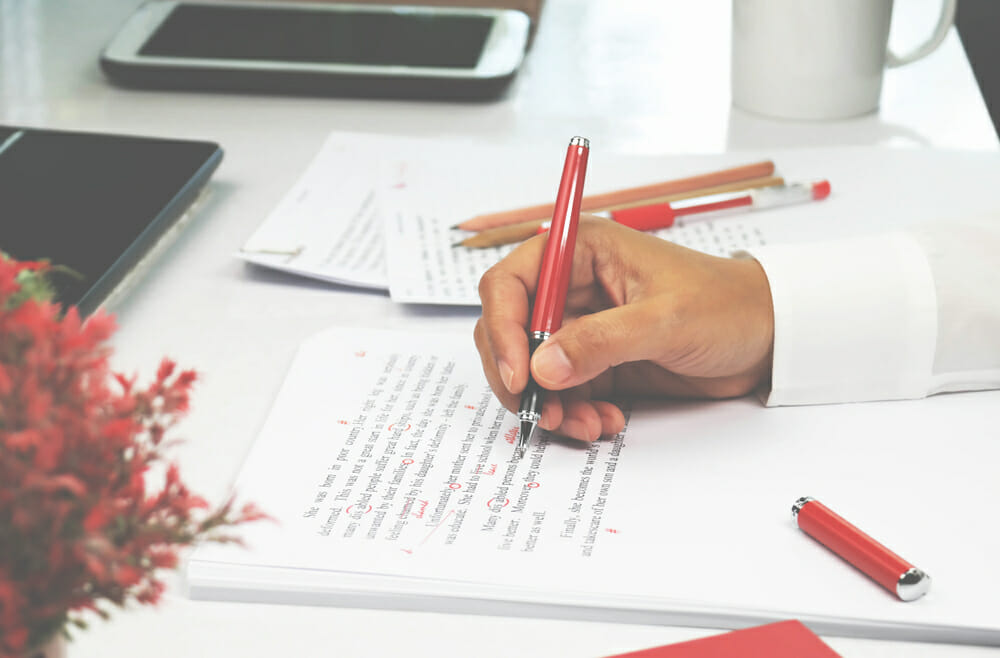 Close up of someone editing a piece of writing with a red pen